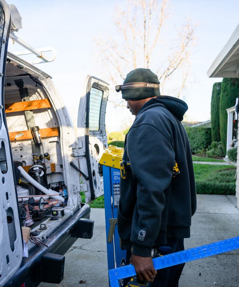 Electric Air technician preparing equipment beside a service van